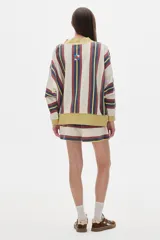 Buzo de algodón lavado a rayas rosas y azul marino, de fit oversized, manga larga y hombros caídos. Cuello en V, terminaciones a contratono y parche en el frente.