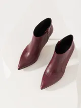 Bota corta de cuero vacuno color borgoña con estampado croco, taco aguja y cierre lateral.