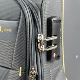 Valija de cabina gris de material textil con detalles en amarillo. Tiene un compartimento interno con cierre, un compartimento externo con cierre, candado TSA y cuatro ruedas. Pesa 2,3 kg.