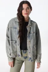 Campera de denim celeste con efecto lavado, corte recto, cuello camisero, cierre frontal con botones metálicos, bolsillos de parche en el pecho y laterales.