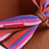 Sandalias Havaianas You St Tropez con base marrón y tira de tela estampada con rayas de colores y nudo decorativo.