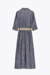 Vestido camisero azul con cinturón de rafia, de cuello solapa y manga tres cuartos con trabilla y botón. Tiene bolsillos de parche en el delantero y cierre frontal con botones.