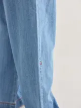 Pantalón gris de tiro medio alto, corte ancho, con bolsillos delanteros y traseros, detalles de atraques y triples costuras en color amarillo.