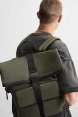 Mochila verde militar con acabado engomado y base de cuero sintético negra. Tiene compartimento principal con cierre de solapa con cremallera y hebilla de liberación rápida, bolsillo interior con cremallera, compartimento para dispositivos electrónicos de hasta 13 pulgadas, bolsillo frontal con cierre imantado, asa de mano, asas de hombro ajustables y parte posterior acolchada.