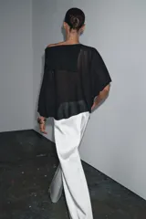 Top color crema de tejido de punto, con cuello asimétrico y mangas anchas.