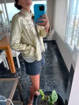 Campera de cuero ovino italiano color dorado, estilo motoquero, con cuello clásico, cierre frontal asimétrico y bolsillos con cierre.