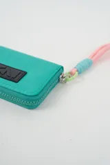 Billetera compacta de color fucsia con cierre perimetral y parche frontal con logo CNI en negro. Incluye una correa de muñeca de cordón en tonos rosado y celeste con un gancho de sujeción verde.