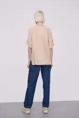 Remera color beige claro, de corte holgado y mangas 3/4 con cuello bote.