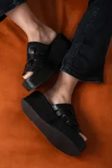 Sandalias negras de cuero con plataforma pareja y tiras de cuero tejidas en la parte superior.