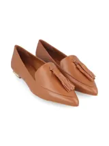 Zapato mocasín color caramelo, de cuero, con punta fina y detalle de borlas. Tiene un pequeño taco cuadrado dorado.