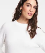 Suéter blanco de punto con textura mousse, cuello redondo y mangas largas.