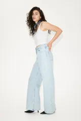 Pantalón jean de tiro bajo en denim bouclé celeste, de algodón rígido, con cinco bolsillos, cierre con botón y corte holgado con piernas amplias.