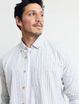 Camisa sport de algodón con cuello button-down y manga larga. Diseño a rayas verticales en tonos gris y blanco. Cierre frontal con botones de madera.