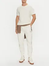 Pantalón de chándal color crema, con cintura elástica ajustable con cordón, puños de canalé, bolsillos laterales y trasero. Presenta el monograma de Calvin Klein bordado en la pierna.