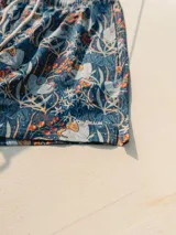 Short de baño azul con estampado floral en tonos blanco, naranja y verde. Tiene elástico en la cintura, cordón ajustable, bolsillos laterales y un bolsillo trasero con botón. Marca Von Braun.