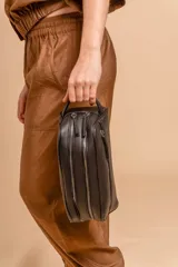Neceser unisex de símil cuero color camel, con forma rectangular y asa lateral. Presenta un bolsillo frontal con cierre vertical y un compartimento principal con cierre superior.