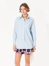Camisa de poplin rayada rosa y celeste, de corte holgado, con cuello clásico, cierre frontal con botones y bolsillo plaqué en el pecho.