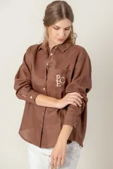 Camisa de lino color gris claro con bordado de monograma PEC en el bolsillo.