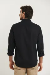 Camisa azul marino de lino y algodón, con cuello abotonado, manga larga con puños enrollados, bolsillo de parche en el pecho y cierre frontal con botones.