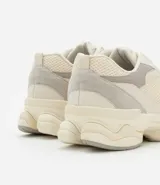 Championes dad sneaker grises con recortes en cuero sintético, cordones blancos y suela chunky de goma color crema.