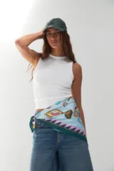 Pañuelo cuadrado de tela fina color celeste con estampado de motivos playeros y borde con diseño geométrico en tonos verde y rosa.