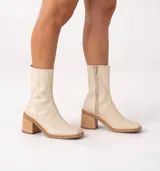 Bota corta color crema con textura de reptil, caña media, punta cuadrada, cierre lateral y taco de madera.