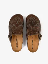 Mules de cuero color marrón con diseño vaquero, costuras decorativas con forma de águila y hebilla lateral ajustable.