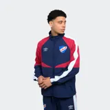 Campera de nylon azul con detalles en rojo y blanco, con cierre frontal y cuello alto. Logotipo de Umbro bordado en el pecho y escudo del Club Nacional de Football en el lado opuesto.