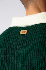 Sweater de punto verde con cuello polo color crema y bordado frontal con texto en blanco.