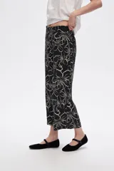 Pantalón capri negro con estampado floral en color crema, de corte ancho y tiro alto.