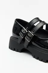 Guillerminas blancas de cuero sintético con suela track negra y doble tira ajustable con hebillas metálicas.