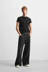 Pantalón de jean negro de corte amplio, con cinco bolsillos, efecto lavado y cierre frontal con cremallera y botón.