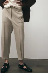 Pantalón tobillero negro de tiro medio con cintura elástica en la espalda, bolsillos delanteros y bolsillos de parche con solapa en la parte trasera. Bajo acabado con pinzas. Cierre frontal con cremallera y botón.