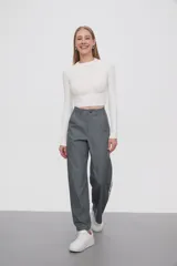 Pantalón gris de calce ancho y tiro alto, con bolsillos laterales y apliques de dos líneas blancas verticales en los laterales.