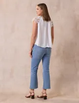 Blusa blanca de crepe marca Liv Los Ángeles, con hombros con aplique en crochet y espalda con abertura ojal y botones.