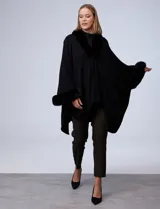 Ruana o poncho negro de tejido suave, con cuello y puños adornados con apliques de piel sintética (faux fur).