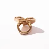 Anillo dorado con forma de corazón con textura irregular.