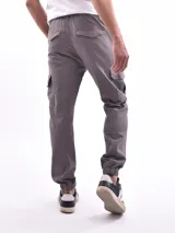Pantalón jogger cargo color verde militar con cintura elástica ajustable con cordón, bolsillos laterales y bolsillos cargo con solapa en los muslos.