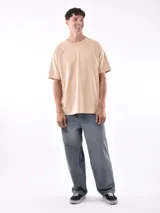Remera gris de corte oversized, cuello redondo y mangas cortas. 