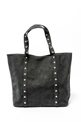 Bolso tipo shopper color negro con apliques de tachas plateadas en los bordes y las asas.
