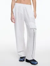 Pantalón de lino blanco con elástico en la cintura, calce relajado, bolsillos laterales y un bolsillo tipo cargo. Detalles de bordado tipo pespunte en color contraste a lo largo de la pierna y en el bajo.