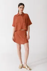 Minifalda color ladrillo con rayas verticales finas y botones dorados en el lateral.