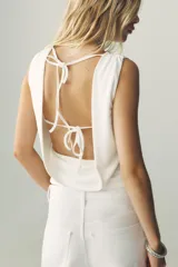Top negro de cuello redondo y tirantes anchos. Detalle de escote en espalda con tira cruzada ajustable con lazada.