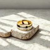 Anillo dorado de acero quirúrgico con banda central negra con números romanos y banda inferior con circonias blancas.