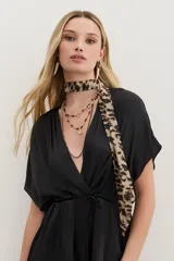 Pañuelo largo de poliéster con estampado animal print en tonos beige y negro.