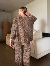 Conjunto de buzo y pantalón de punto con estampado animal print en tonos beige y negro. El buzo es de corte holgado y el pantalón es de corte recto.