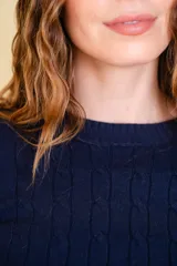 Buzo tejido color azul marino, con diseño de trenzas en la misma tela y corte ajustado.