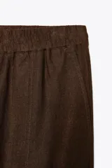 Pantalón bombacho color beige de lino, con cintura elástica, bolsillos frontales y bolsillos de parche en la espalda.