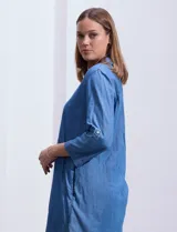 Vestido corto de tencel color azul denim, con cuello solapa, escote en V y mangas 3/4 regulables con presilla y botón.