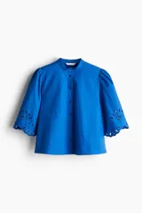 Blusa azul eléctrico de algodón con cuello mao, botones frontales, manga 3/4 abullonada con bordado calado y puños festoneados.